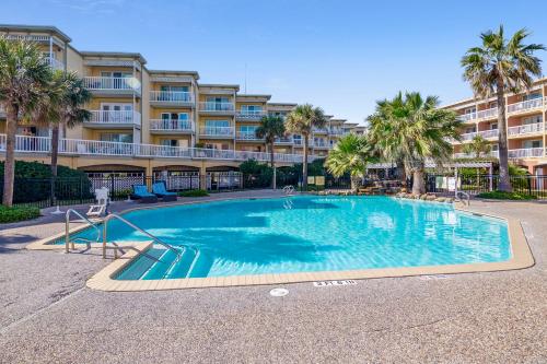 a swimming pool in front of a building with palm trees at Victorian 9203-Ocean Oasis in Galveston