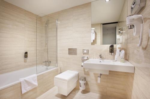 a bathroom with a tub, toilet, sink and mirror at Grandior Hotel Prague in Prague