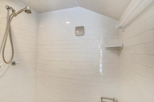 a white tiled shower with a shower head in a bathroom at AbFab Seaside Cottage in Galveston