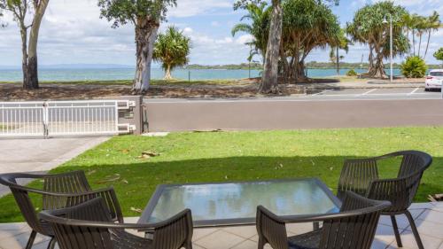 a patio with chairs and a table with a view of the water at Magical holiday home - Welsby Pde, Bongaree in Bongaree