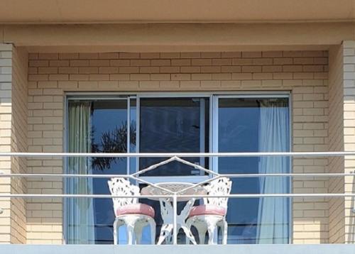 un balcone con tavolo e sedie di fronte a una finestra. di Mollymook Ocean View Motel Rewards Longer Stays -over 18s Only a Mollymook