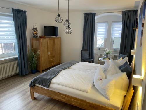 um quarto com uma cama, uma televisão e janelas em Haus Herzog em Bad Steben