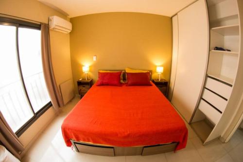 1 dormitorio con 1 cama roja y 2 almohadas rojas en DEPTO CENTRO GODOY CRUZ CON COCHERA en Godoy Cruz