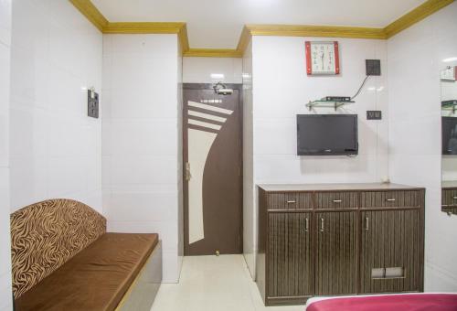 Habitación con banco, TV y puerta en RELAX GUEST HOUSE en Bombay