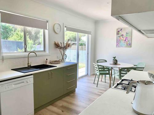 a kitchen with a sink and a table with chairs at COD & C0 Tocumwal in Tocumwal