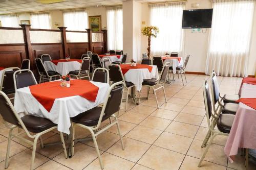 Hotel Palace Ejecutivo في سان بيدرو سولا: غرفة طعام مع طاولات وكراسي حمراء وبيضاء