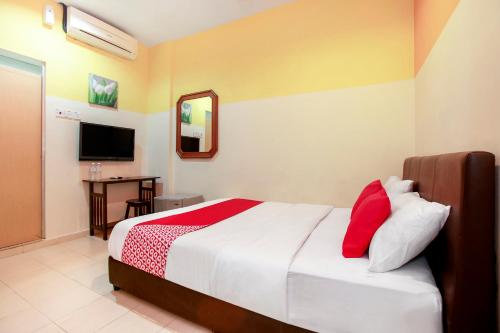 a bedroom with a bed and a desk and a television at OYO 43933 Ferringhi Stay Iinn in Batu Ferringhi