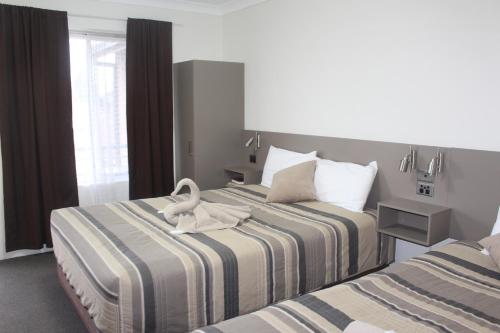 a hotel room with two beds with a swan on it at Centrepoint Motel in Dubbo