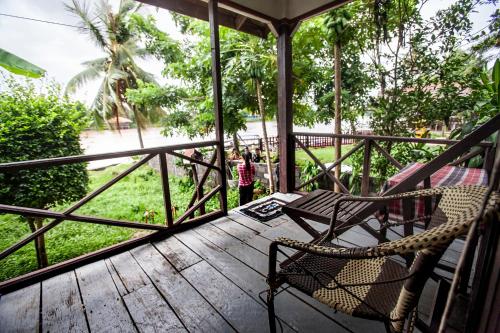 a rocking chair on a porch with a view of the street at Lao Long Riverside and Budget Garden Guesthouse in Ban Khon