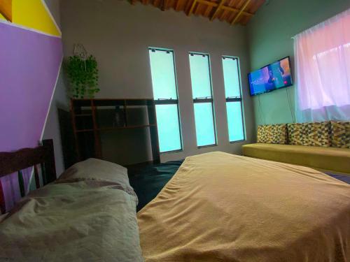 1 dormitorio con cama, sofá y ventanas en Casa Lunna Paraty - Praia e cachoeira, en Paraty