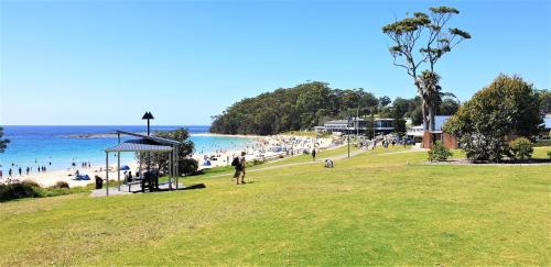 a group of people on a beach near the water at Mollymook Ocean View Motel Rewards Longer Stays -over 18s Only in Mollymook