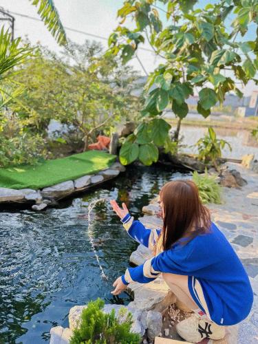 a woman is playing in the water at a pond at Ninh Binh Royal Homestay in Ninh Binh