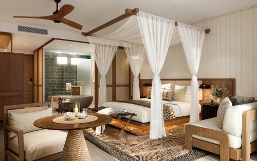 a bedroom with two beds and a table in a room at InterContinental Lifou Wadra Bay Resort in Akaouane