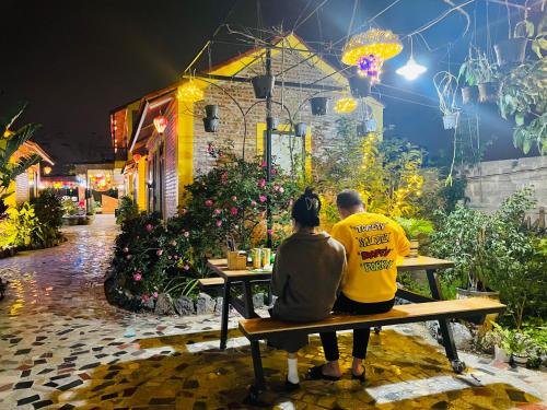 a man and woman sitting on a bench in a garden at Ninh Binh Royal Homestay in Ninh Binh