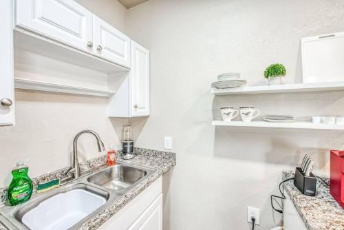uma cozinha com um lavatório e armários brancos em Stylish Studio 89 Brand New from the floor up em Fresno