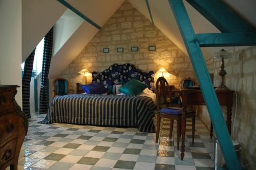 a bedroom with a bed and a desk in a room at Logis Demeure de la Vignole in Turquant