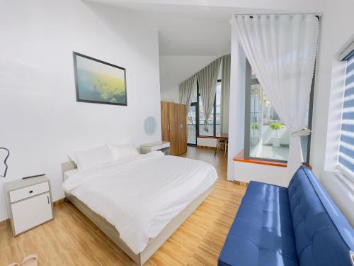 a bedroom with a white bed and a blue couch at Dalat Family Hostel in Da Lat