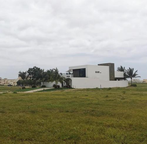 a white building in a field with a grass field at G R A N D C H A L E T in Salalah