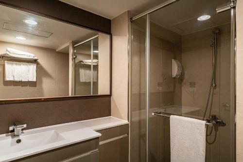 a bathroom with a sink and a shower with a mirror at Global Traveler Hotel in Kaohsiung
