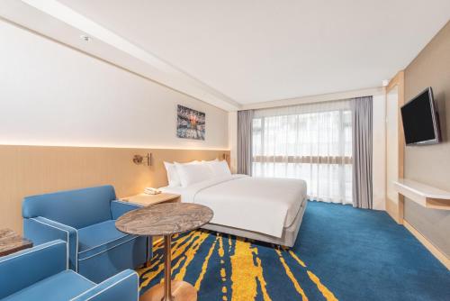 香港にあるホリデイ イン ゴールデン マイルのベッド、テーブル、椅子が備わるホテルルームです。