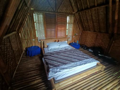 1 dormitorio con 1 cama en una habitación de madera en Girang Rinjani Bungalows, en Tetebatu