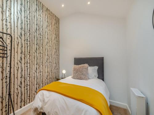 a bedroom with a bed with a yellow blanket at The Cottage in Langsett