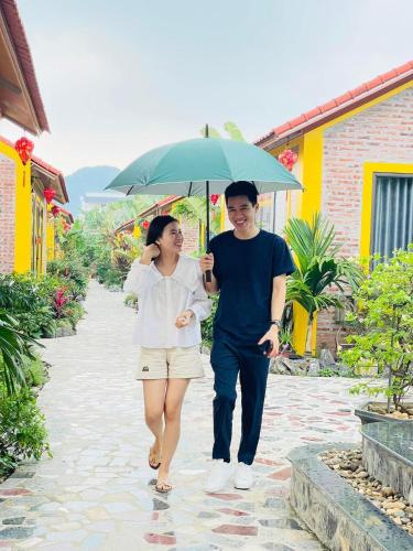 a man and a woman walking down a sidewalk with an umbrella at Ninh Binh Royal Homestay in Ninh Binh