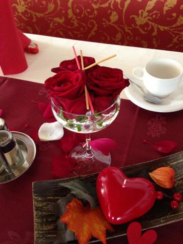 a glass bowl of red roses and a cup of coffee at Hotel Thaler in Rietz