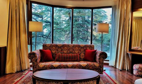 a living room with a couch and a large window at Royale Retreat Hotel & Spa Near Mall Road in Shimla