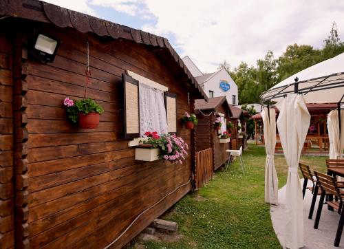 a wooden house with flowers on the side of it at Pensiunea Casa Doamnei Voronet in Gura Humorului