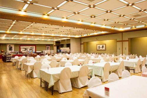 een grote feestzaal met witte tafels en stoelen bij Takuboku Tei in Hakodate