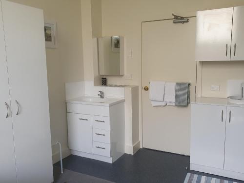 a white bathroom with a sink and white cabinets at Work Stay at 123 in Dunedin