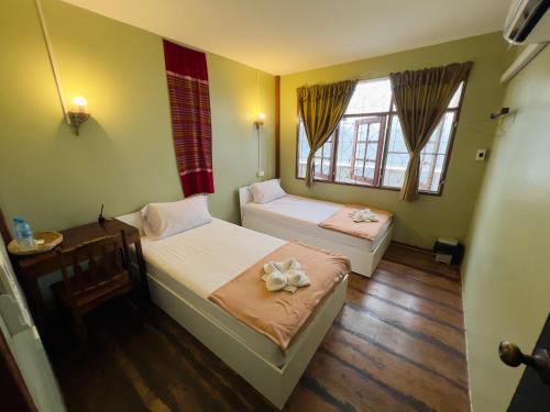 two beds in a room with two windows at DonMueang Boutique House DonMueang Airport in Bangkok