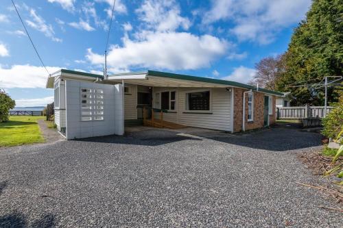 a small white building with a garage at Daydream house, Sunrise, sunset views across lake in Rotorua
