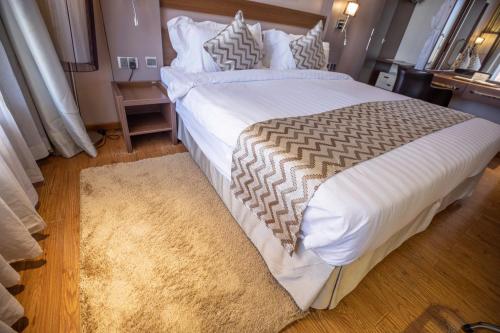 a bedroom with a large white bed with a rug at Ngong Hills Hotel in Nairobi