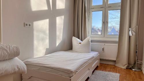 ein weißes Zimmer mit einem Bett und einem Fenster in der Unterkunft Haus MeerZeit Whg.2 in Cuxhaven