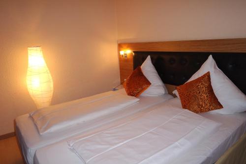 a bed with white sheets and pillows next to a lamp at Hotel Drei Kronen in Dortmund