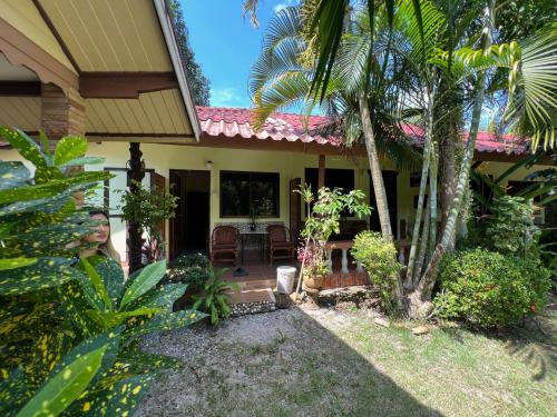 ein Haus mit einer Veranda und Palmen in der Unterkunft Garden Bungalow Resort in Thai Muang
