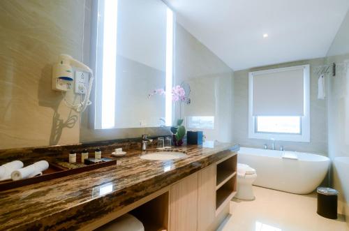 a bathroom with a sink and a tub and a toilet at The Excelton Hotel in Palembang