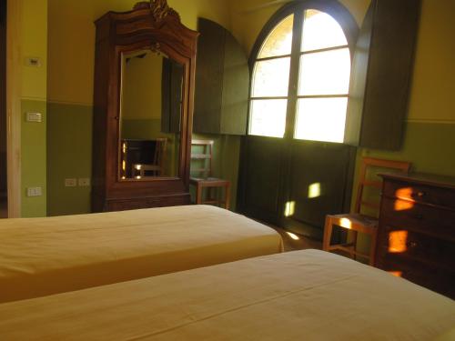 a bedroom with two beds and a mirror and a window at Agriturismo Serracanina in Cagli