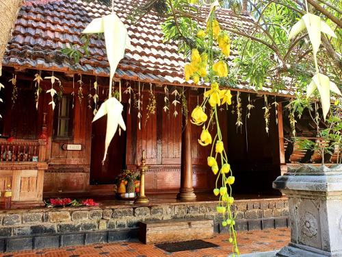 a building with a wooden door with yellow flowers at Thriphala Ayurveda Yogashram in Trivandrum
