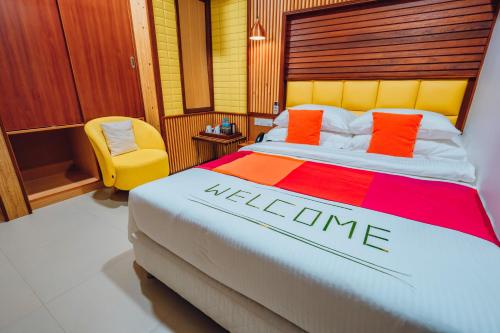 a hotel room with a bed and a yellow chair at Millennium Island Residence in Fuvahmulah