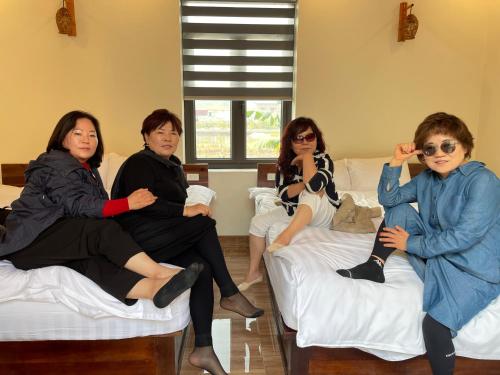 four women sitting on beds in a room at Ninh Binh Royal Homestay in Ninh Binh