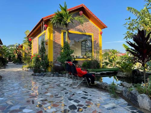 a person sitting in a chair in front of a house at Ninh Binh Royal Homestay in Ninh Binh