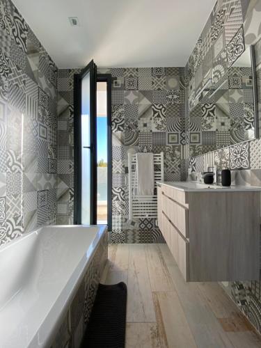 een badkamer met een groot bad en een wastafel bij La Villa Blanche in Saint-Cézaire-sur-Siagne