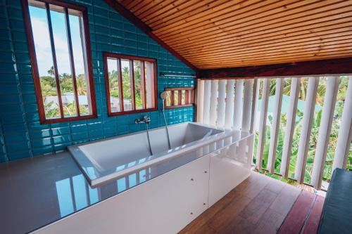 a bathroom with a large tub in a room with windows at Millennium Island Residence in Fuvahmulah