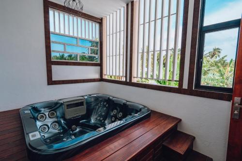 Millennium Island Residence في Fuvahmulah: وجود حوض استحمام جالس في غرفة بها نافذتين