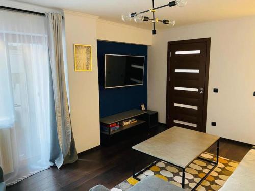 - un salon avec une table et une télévision dans l'établissement Aparthotel City Center Targu Ocna, à Tîrgu Ocna