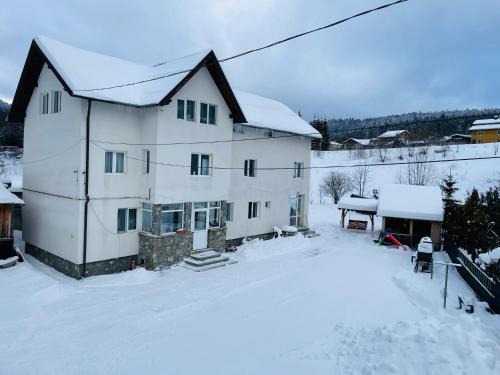 a large white house with snow on the ground at Casa Korina in Azuga