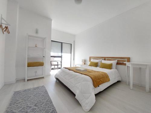 a white bedroom with a large bed and a table at Aveiro Home in Aveiro